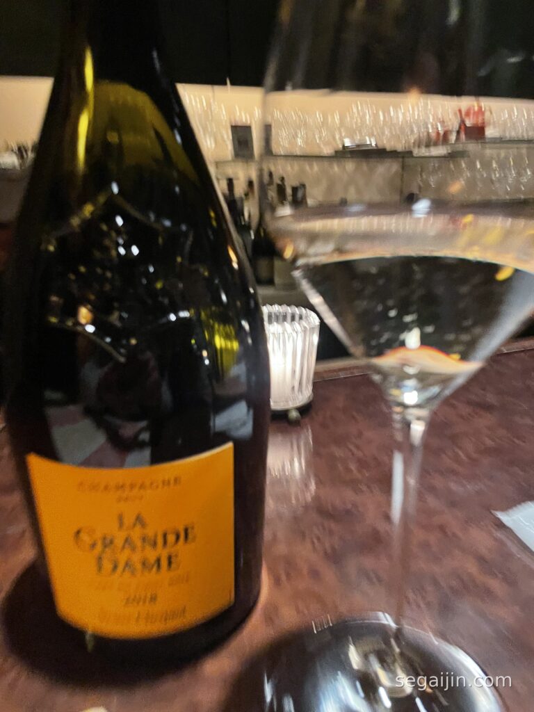 A bottle of Champagne and a glass on a bar counter in warm evening light