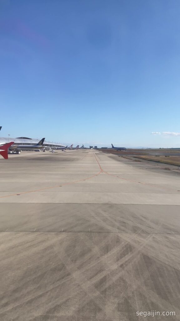 A long airport runway stretching straight toward the horizon under a wide blue sky