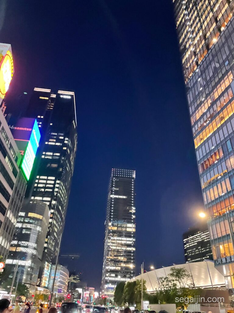 Skyscrapers lit up at night, seen from the street looking up