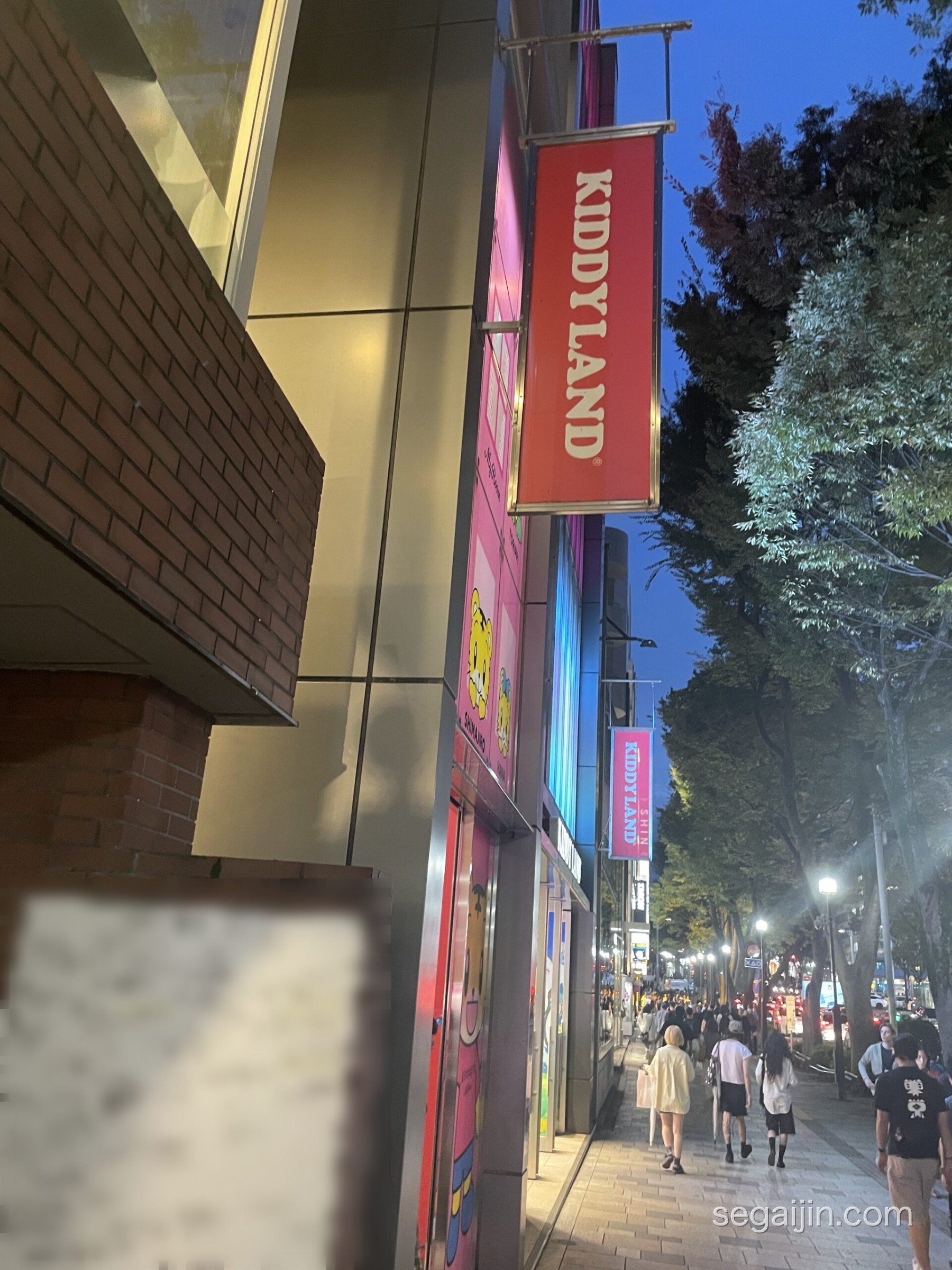 The Kiddy Land sign on a tree-lined street in Omotesando at dusk